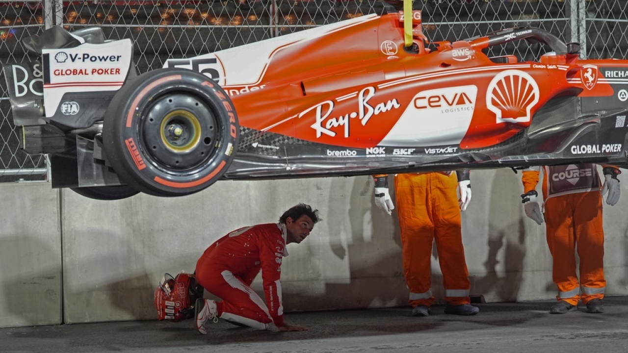 Ferrari driver Carlos Sainz of Spain looks at the bottom of his car after running over a manhole cover